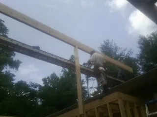 Carpenter setting a ridge beam over a new addition frame — Ice Dam Removal by Roofing Brothers in Pulaski