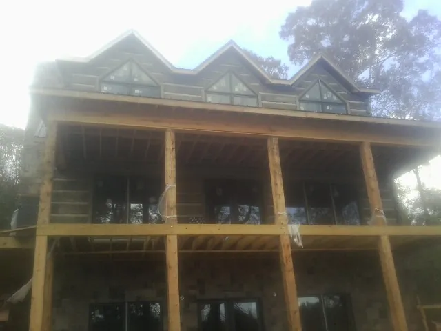 Dormers and porch framing on a large log home under construction — Roof Coating work by our crew in Pulaski