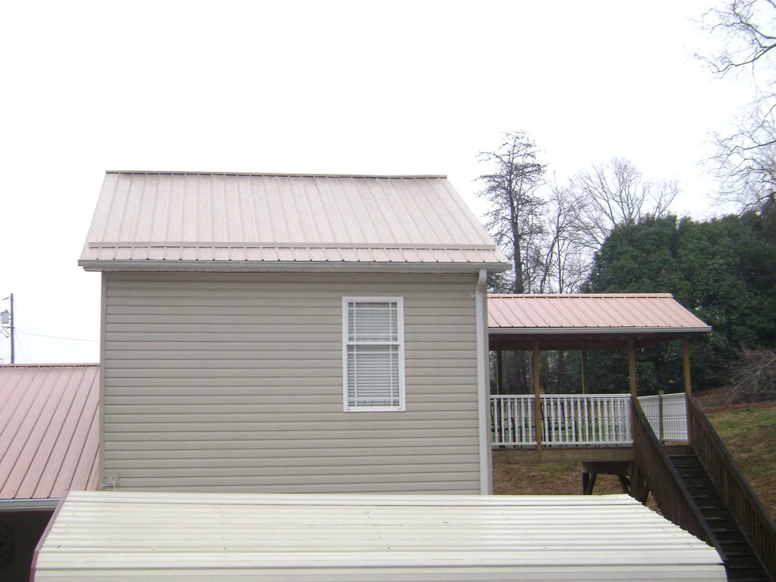 Tan metal roofs on a two story addition and attached porch, from a Roof Replacement job in Pulaski